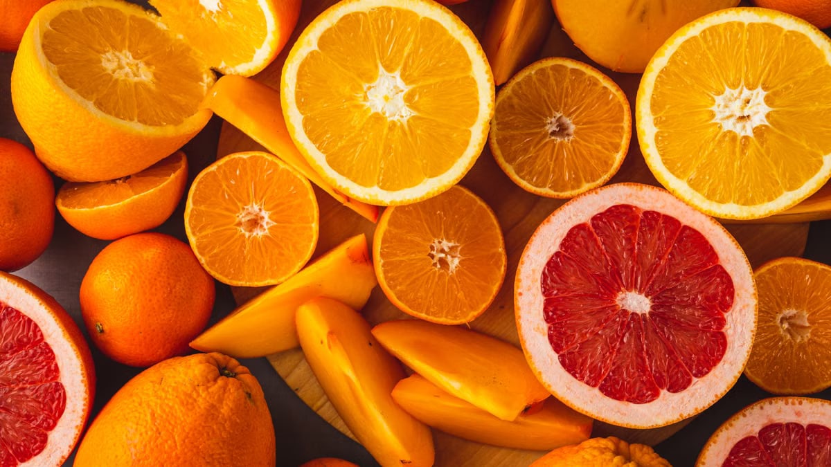 Vibrant close-up of assorted citrus and tropical fruits including oranges, grapefruit, and persimmons.