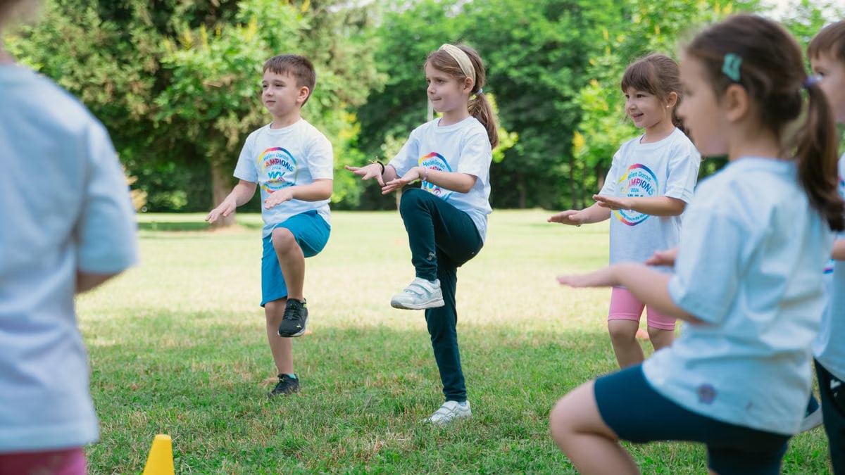 Group of children playing and exercising outdoors in a sunny park setting.